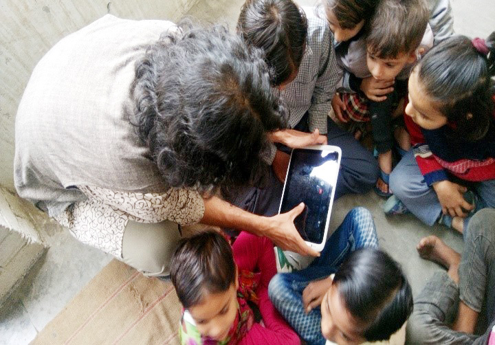 “Children learning to use a tablet during Mobile Library’s visit in Aurangabad Village in Haryana ” by Dr Rangashri Kishore is licensed under CC BY 4.0